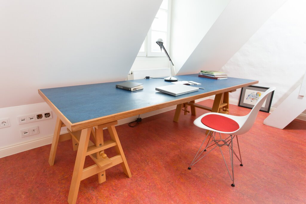 Die Arbeitsplatte des Schreibtisches und der Fußboden sind mit Linoleum bedeckt.